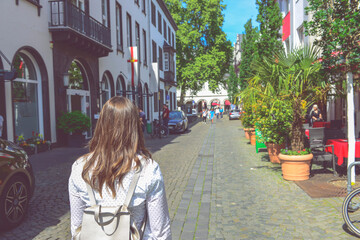 Fototapeta premium Girl In Shirt With Leather Backpack Walk By Old Town Street