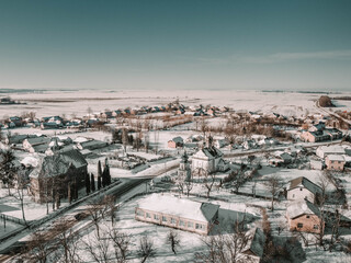 Aerial view to the Ukrainian village from above during winter, with two churches in the frame. Everything covered in snow. 