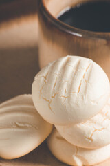 Small round cookies and Cup of coffee in brown dish on wooden table.