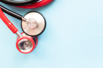 Medical equipment: two stethoscopes - red and black laying together on a light blue backround with a place for text. Copy space. Medical concept.