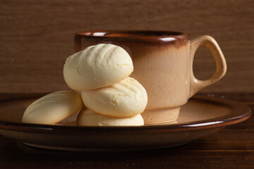 Small round cookies and Cup of coffee in brown dish on wooden table.