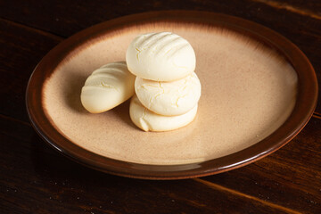 Small round cookies and Cup of coffee in brown dish on wooden table.