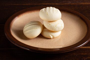 Small round cookies and Cup of coffee in brown dish on wooden table.