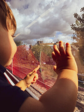 One year boy looking on the street thru a train window. 