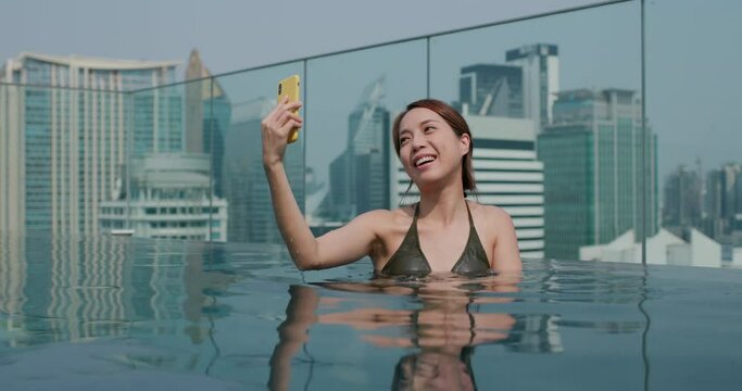 Woman take selfie on cellphone in swimming pool