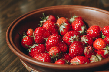 Strawberries in a plate on the wooden board. Summer concept.
