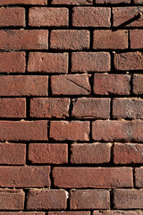 Vertical, full-frame, wall surface from worn red brick texture, photographed in daylight in the city of Amsterdam