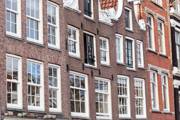 Fototapeta na wymiar Horizontal full-frame, detail view of classic, traditional red brick buildings in Amsterdam. Classic residential architecture in the capital of The Netherlands under soft even light