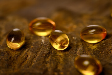 Obraz na płótnie Canvas Vitamin capsules. Soft gel capsules on the surface of natural stone. Сlose up fish oil on gold background. Omega 3. Сoncept of health. Омега 3. gold pattern