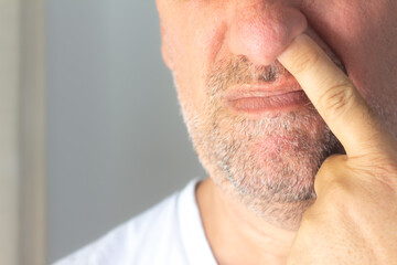 Naklejka premium Caucasian middle-aged man with slightly grown beard. man with his finger up his nose.