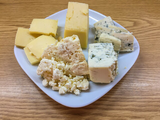 Several types of rustic cheese on a plate.