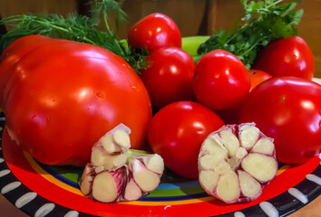 Tomatoes, garlic and herbs on a plate. Natural organic food, set of various fresh vegetables over.