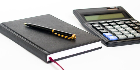 Calculator pen and notebook on white background.