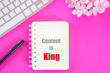 content is king word on notebook with laptop keyboard,pen flat lay on pink background ,business...