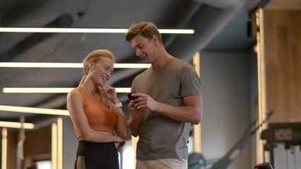 Beautiful fit couple flirting at gym. Fit man writing phone number in sport club