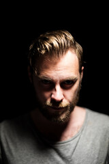 A bearded caucasian male model looking intensely
at the camera wearing a gray shirt