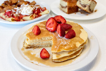 Pancakes with Strawberries and Syrup on a White Table
