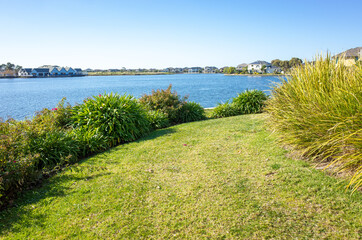 Fototapeta premium View over the shore of Sanctuary Lakes with some luxury waterfront houses in the distance. Point Cook, Melbourne, VIC Australia.