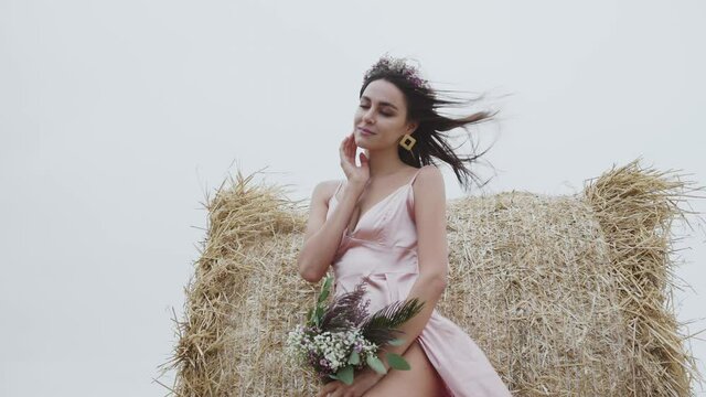Passionate lady poses gently with joy at haystack in spacious windy field