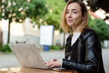 Blonde girl resting after working on a laptop in the city. Freelancer