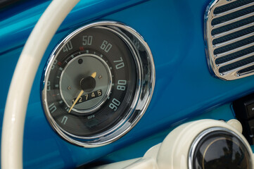 Stylish speedometer dial on the front panel of blue old timer car