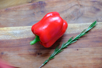 Fresh rosemary and sweet red bell pepper on a wooden background. The concept of a delicious and healthy diet.