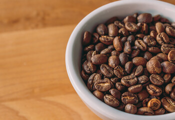 Light Roast Coffee Beans in White Cup on Light Wood Background