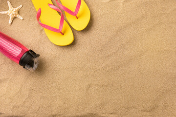 Fototapeta na wymiar Top view flip flops and water bottle with copy space. Traveler accessories on sand. Travel vacation concept. Summer background. Border composition made of towel