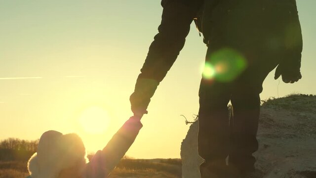 work in team of tourists. young woman hiker climbs mountain holds out helping hand. Free female traveler climb mountain holding hands. climbers traveler climbs mountain. trip to mountains at sunset.