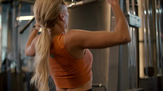 Strong sport woman making pulldown at gym. Fit girl training in sport club