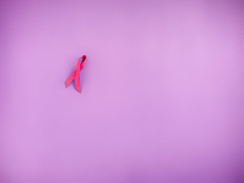 Cancer Awareness Celebration Concept - Pink ribbon with purple vintage background. Stock photo.