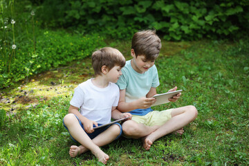 Two brothers play a touchpads on the grass