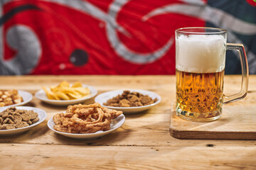 A glass of beer and different snacks on the table. Celebrating international beer day or Octoberfest. Drinking beer after a hard working day or week