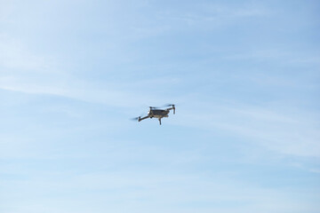 Drone flying in blue sky with clouds in the background. Drone flying overhead in cloudy blue sky. Drone quad copter with high resolution digital camera on the sky.
