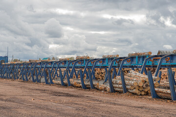 Fototapeta na wymiar Round timber logs preparation sorting processing at sawmill. Wheel loader and automatic sorting logs diameter at the sawmill. Lumber industry.