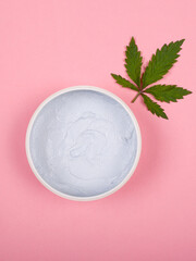 skin care with medical marijuana. green cannabis leaf and cream on a pink background