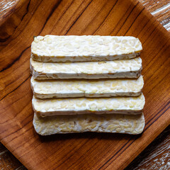 Raw tempeh or tempe, traditional Indonesian soy product on a wooden tray. Top view. Bali, Indonesia.