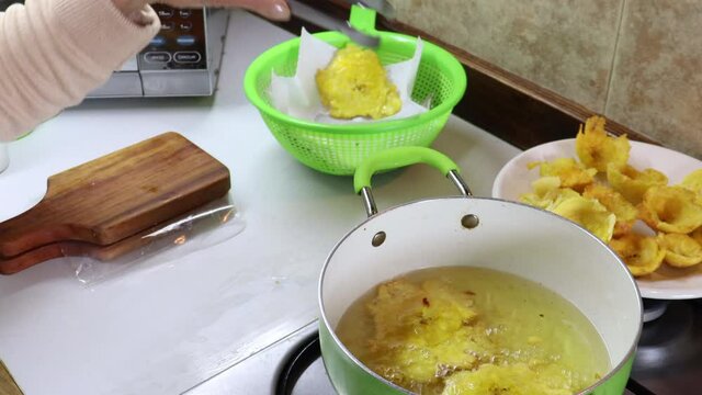 Frying traditional plantain smashed pieces called patacones or tostones