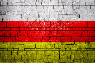National flag of Ossetia on brick  wall background.The concept of national pride and symbol of the...