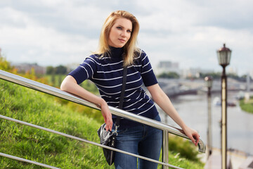 Young fashion woman in striped turtleneck t-shirt leaning on railing