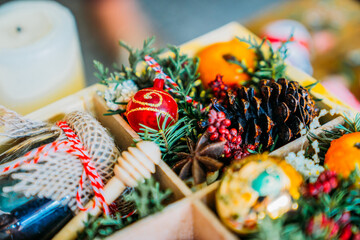 Close up of christmas wooden gift box with christmas toys, honey, pice cone, branch and star anise