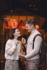 newlywed couple eating noodles with chopsticks in Shanghai outside a food market near Yuyuan. Couple eating authentic local food. husband and wife eating chinese food outisde of a food hall