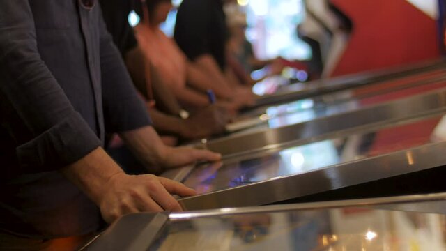 Man getting frustrated while playing at a pinball table in an arcade