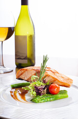 Grilled salmon fillets and fresh salad, served with a bottle of wine.
