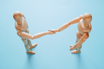 青背景で握手をする木製のモデル人形