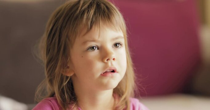 Adorable little girl in the sunlit living room watching tv and eating cereals