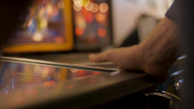 Close-up on a man's hands getting frustrated while playing pinball at an arcade