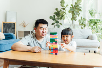 Asian father and daughter are doing puzzle game