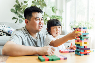 Fototapeta premium Asian father and daughter are doing puzzle game