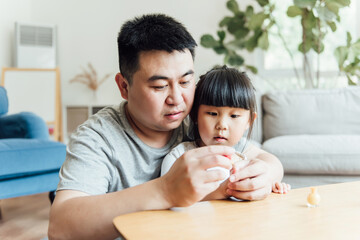 Asian father and daughter are applying nail polish